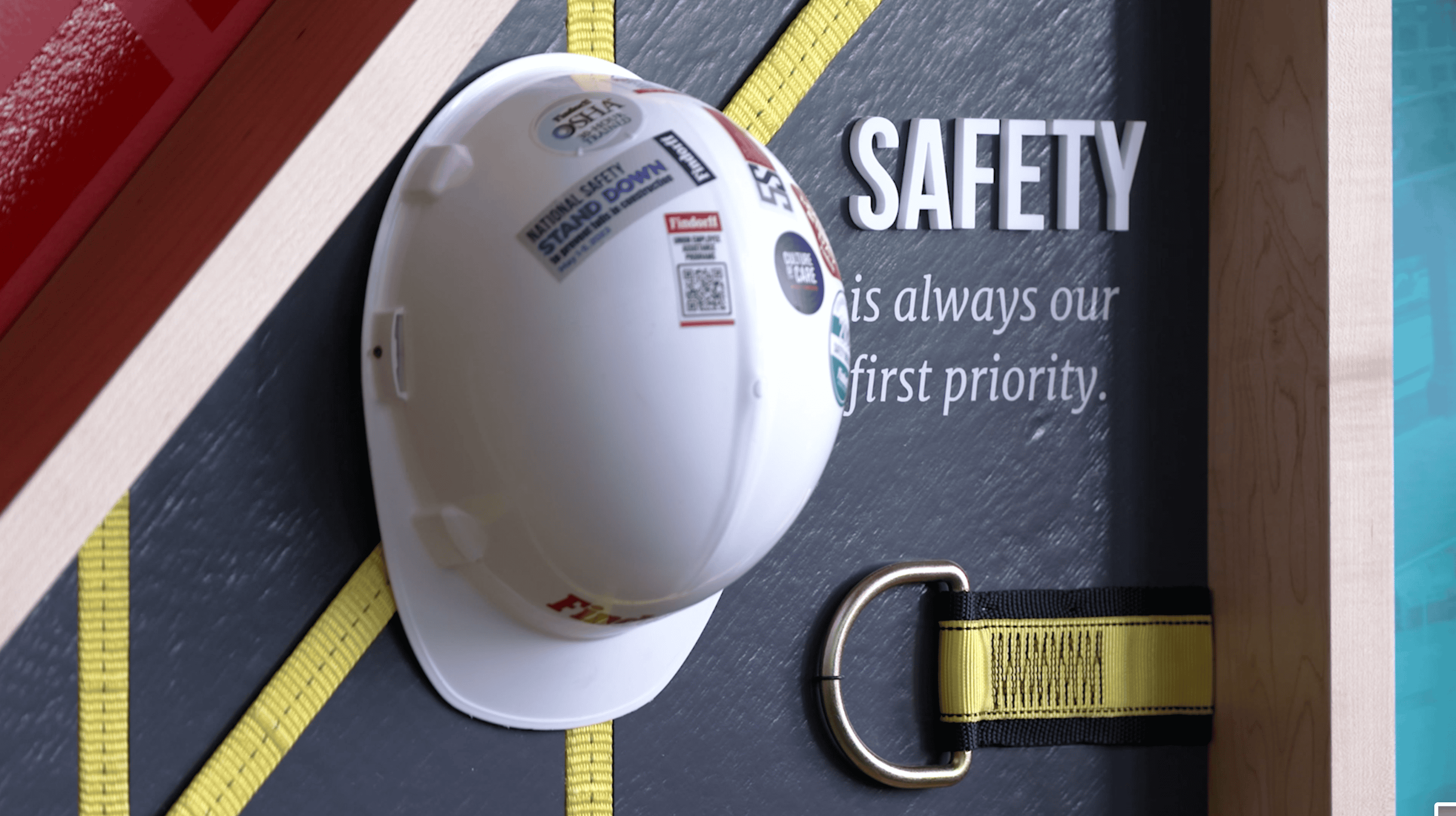 Findorff facility branding display by Thysse featuring a hard hat with safety messaging, emphasizing 'Safety is always our first priority,' alongside tools and equipment against a branded, visually engaging backdrop.